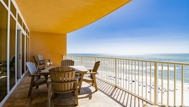 Ein Balkon mit Blick auf den Strand, ausgestattet mit Holzstühlen und einem Tisch.