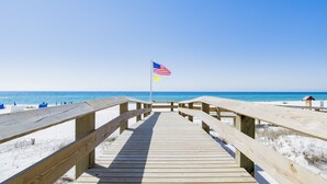 Ein hölzerner Steg führt zu einem Strand, an dessen Spitze ein Fahnenmast mit der US-Flagge steht.