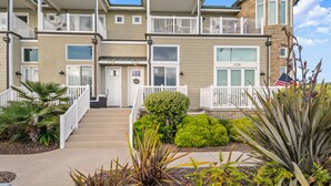 A multi-story residential building with a front entrance, a covered porch, and a landscaped front yard. - Sunset Dreams on the 101 (Carlsbad)