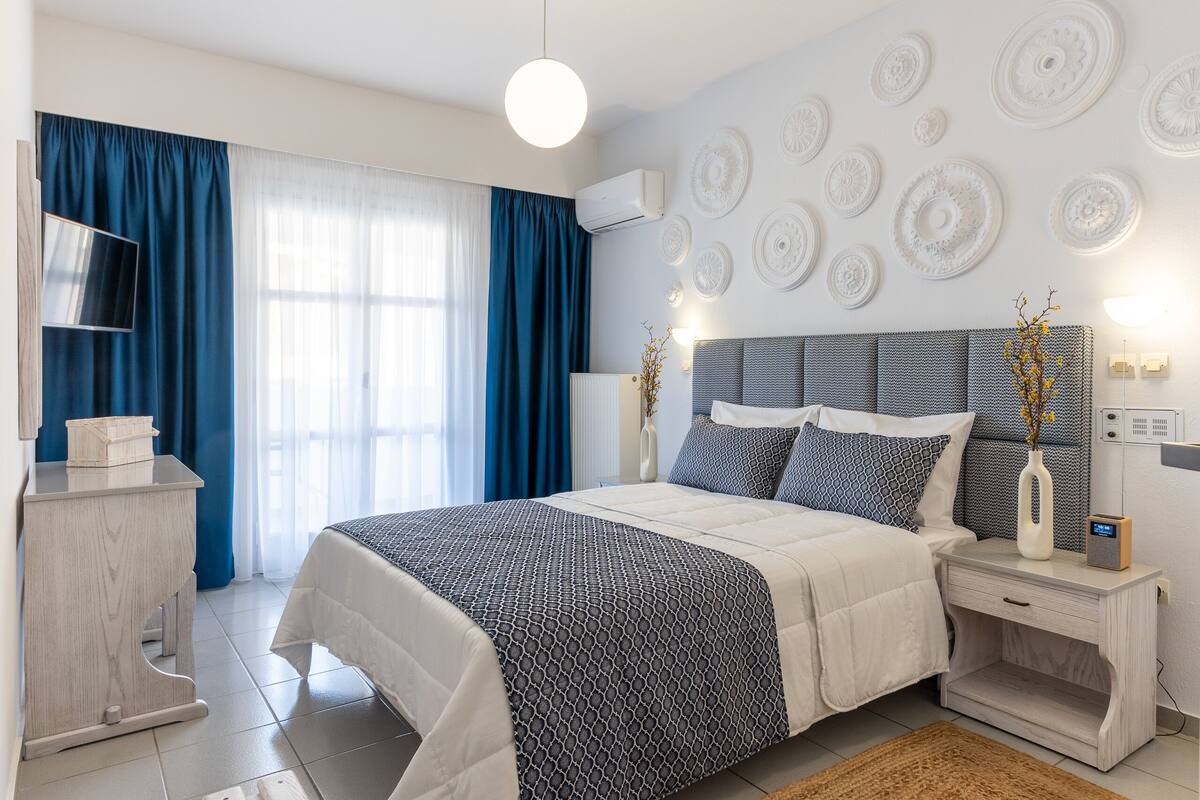 Un dormitorio con cama, mesitas de noche, televisor y elementos decorativos en la pared.