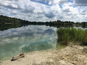 Un lac paisible aux eaux claires, où le ciel et les arbres environnants se reflètent.