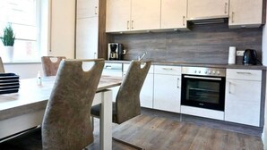 Uma cozinha moderna com armários brancos, forno embutido e cafeteira.