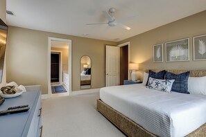 A bedroom with a bed, bedside tables, a mirror, and a ceiling fan.