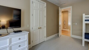 Een kamer met een witte dressoir, een televisie aan de muur, een gesloten deur en een stapelbed.