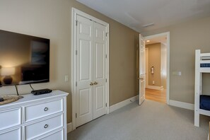 Ein Zimmer mit einem weißen Schminktisch, einem an der Wand befestigten Fernseher, einer geschlossenen Tür und einem Etagenbett.