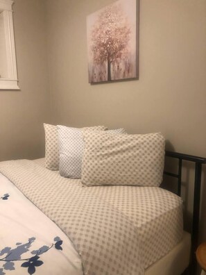 Un dormitorio con cama, almohadas y un cuadro colgado en la pared.