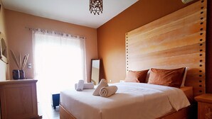 A neatly made bed with a wooden headboard, a bedside table, and a mirror on the wall. - Villa MATA - 600m² with Private Pool and Jacuzzi (Kalithies)