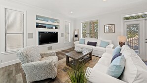 A spacious living room with a white sofa, patterned armchair, and a coffee table. - Luxe Destin Miramar Beach Walk to Beach, Private Heated Pool (Destin)