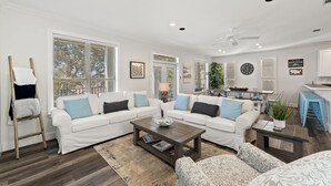 A spacious living room with a white sectional sofa, a wooden coffee table, and a patterned armchair. - Luxe Destin Miramar Beach Walk to Beach, Private Heated Pool (Destin)