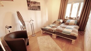 Een slaapkamer met een bed, een stoel, een staande lamp en een raam met gordijnen.