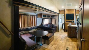 Un intérieur de camping-car compact comprenant un coin repas, des sièges et une petite cuisine.
