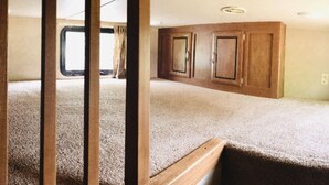 Un intérieur de camping-car compact comprenant un coin cuisine, une fenêtre et une porte.