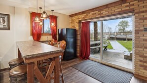 Una cocina con encimera de granito, taburetes de madera, un refrigerador negro y una puerta corrediza de vidrio que da a un patio.