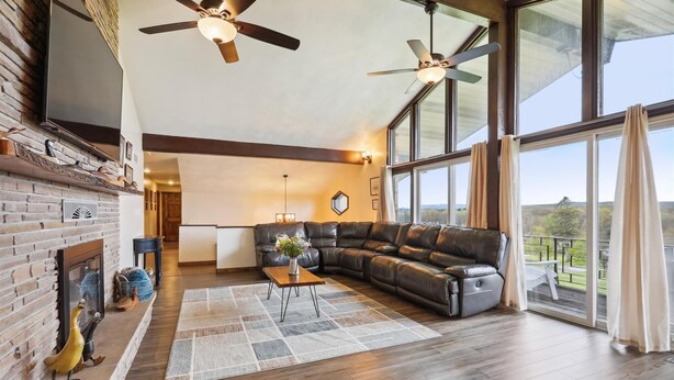 Un salón amplio con un sofá de cuero grande, una chimenea y vistas al exterior a través de grandes ventanales.