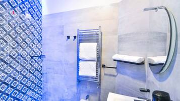 Um banheiro moderno com parede revestida de azulejos estampados, um porta-toalhas com duas toalhas, uma pia e um espelho.
