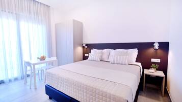 Quarto de hotel com uma cama grande, uma escrivaninha e uma cadeira.