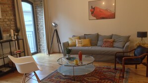 A living room with a sofa, two chairs, a coffee table, a rug, a lamp, and a painting on the wall. - Stylish loft near the Danube (Budapest)
