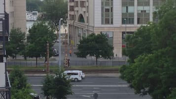 A multi-story building with large windows and a flat roof, surrounded by trees and a street with cars.