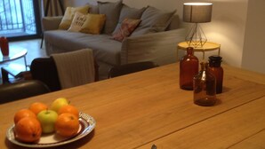 A wooden table with a plate of fruit, a mug, and a lamp in a room with a sofa and a painting on the wall. - Stylish loft near the Danube (Budapest)