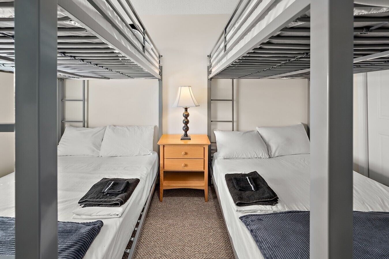 Une chambre avec deux lits superposés, une table de chevet et une lampe.