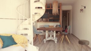 Un soggiorno moderno con una scala a chiocciola, un'area pranzo con un tavolo e sedie in legno, e un'accogliente angolo relax con un tappeto decorato.