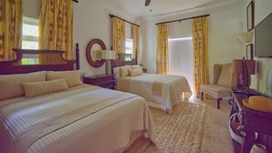 Ein Hotelzimmer mit zwei Betten, einem Deckenventilator, einem großen Spiegel und einem Schreibtisch mit Lampe.