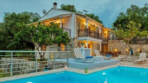 Ein zweistöckiges Steinhaus mit Swimmingpool, Sitzgelegenheiten im Freien und einem Balkon.
