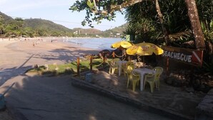A beachside café with outdoor seating and umbrellas, overlooking a sandy beach and the ocean. - Pousada Seachegue (Ubatuba)