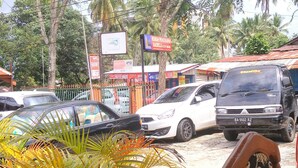 A parking area with several cars, a signboard, and a potted plant. - Rachella Homestay (Tanah Datar)