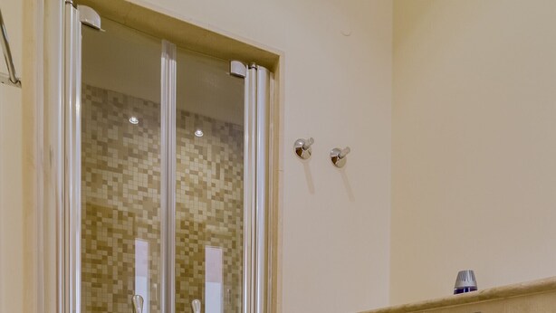 Een badkamer met een douche met glazen wand, een toilet en een wastafel op de muur.
