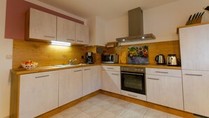 Una cucina moderna con mobili bianchi, un forno a microonde, una macchina per caffè e un fornello.