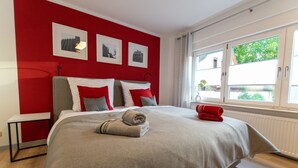 Camera da letto moderna con un letto grande, pareti di colore rosso e quadri appesi al muro.