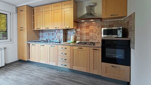 Una cocina moderna con armarios de madera, estufa a gas, microondas y azulejos decorativos para la pared.