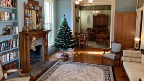Un salon chaleureux avec une cheminée, un sapin de Noël et une bibliothèque remplie de livres.