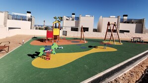 A playground with a slide, swings, and a climbing structure. - Modern Penthouse with a sea view. (Finestrat)
