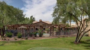 Ein Golfplatz mit Clubhaus, Pool und einem von Bäumen gesäumten, eingezäunten Bereich.