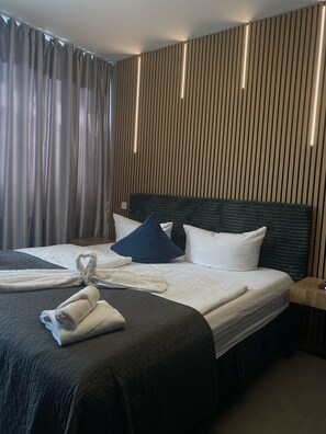 Une chambre d’hôtel avec un grand lit, une tête de lit et une table de chevet.