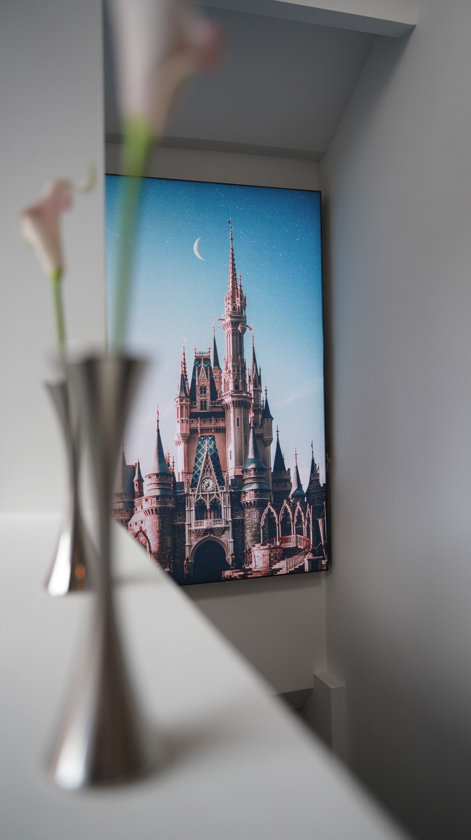 A framed picture of a castle with multiple towers and a crescent moon in the sky.