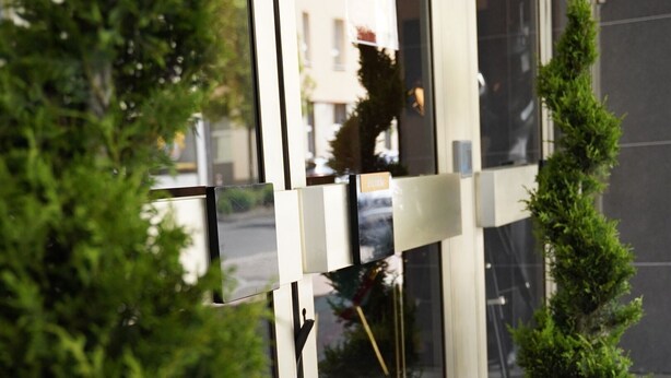 A building entrance with glass doors, a red carpet, and a potted plant. - Amical Hotel Hagen (Hagen)