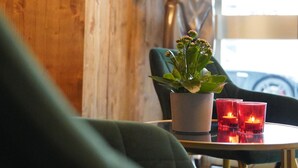 A room with a wooden wall, a statue, a potted plant, and a table with red glasses. - Amical Hotel Hagen (Hagen)