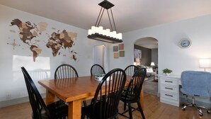 A dining area with a wooden table and black chairs, a world map on the wall, and a clock on the wall.