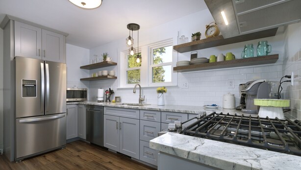 A modern kitchen with stainless steel appliances, wooden flooring, and built-in shelves.