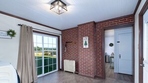 A room with a large sliding glass door leading to a view of a field, a brick wall with a 'I shall not be moved' sign, and a radiator.