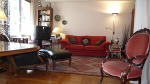 A living room with a red sofa, a wooden coffee table, a television, and a bookshelf. - Typical Parisian neighborhood Easy access (Paris)