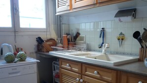 A kitchen with wooden cabinets, a dishwasher, and a sink. - Typical Parisian neighborhood Easy access (Paris)