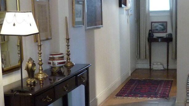 A hallway with a wooden console table, a red patterned rug, and a mirror on the left. - Typical Parisian neighborhood Easy access (Paris)