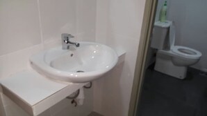 A bathroom with a white sink, toilet, and a small trash bin. - Marina Barrington sq aprt at pasar malam Tanah Rata Cameron Highland (Tanah Rata)