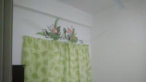 A bathroom with a green leaf-patterned shower curtain, a white wall, and a tropical mural above the curtain. - Marina Barrington sq aprt at pasar malam Tanah Rata Cameron Highland (Tanah Rata)