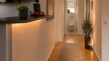 A modern kitchen with a built-in stove, a stainless steel range hood, and a countertop with a potted plant and fruit bowl.