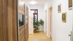 Un couloir avec un plancher en bois, des murs blancs et une plante en pot.